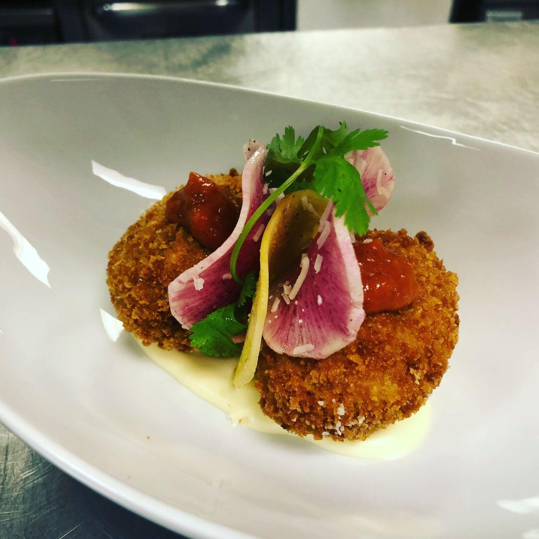 A white plate displaying a crispy fried fish cake, perfectly cooked and presented for enjoyment. A white plate displaying a crispy fried fish cake, perfectly cooked and presented for enjoyment.