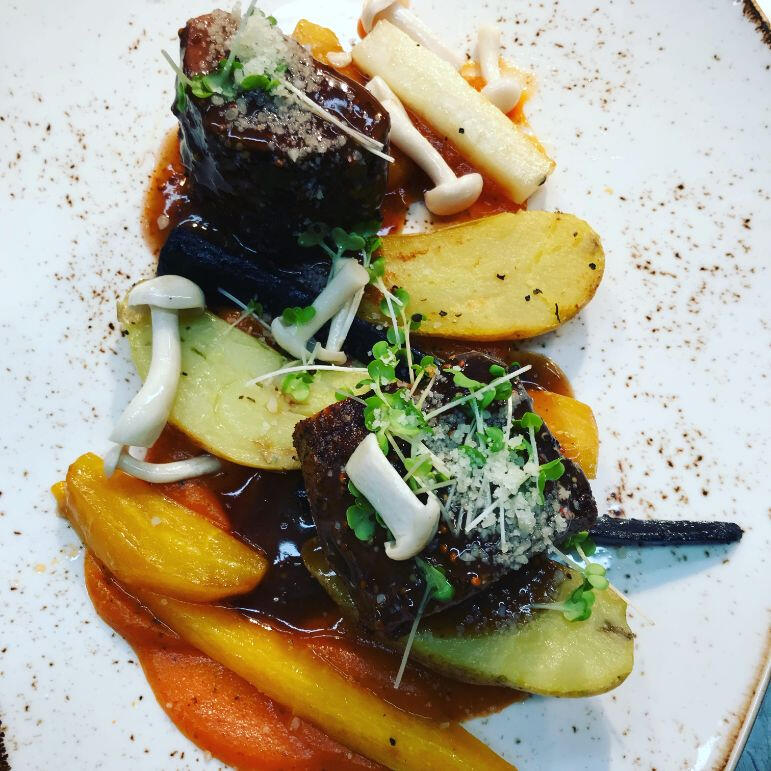 A plate featuring a serving of meat accompanied by potatoes and a variety of colorful vegetables. A plate featuring a serving of meat accompanied by potatoes and a variety of colorful vegetables.